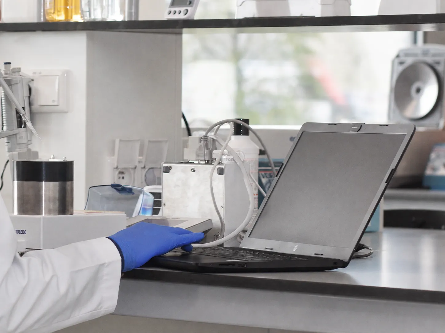 Person in a lab scrolling on laptop to monitor his pipettes